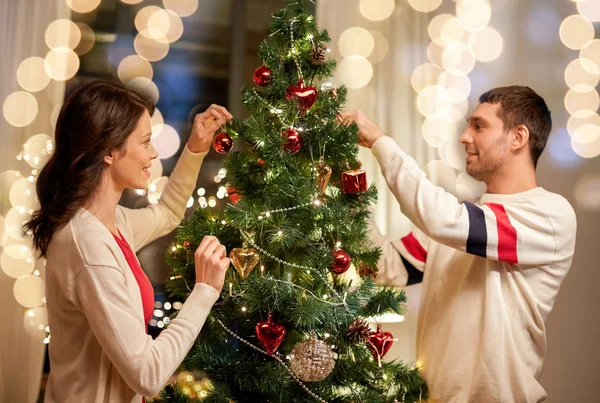 幸せなカップル飾るクリスマスツリー自宅で — ストック写真