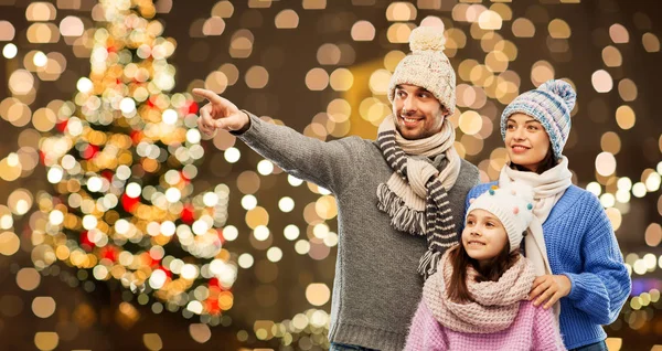 Gelukkige familie in de winter hoeden over Kerstverlichting — Stockfoto