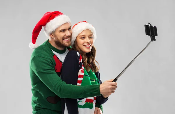 Happy couple in christmas sweaters taking selfie — Stock Photo, Image