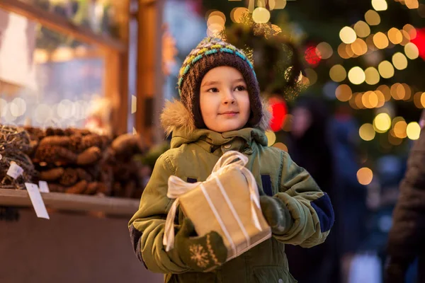 クリスマスマーケットにギフトボックス付きの幸せな男の子 — ストック写真