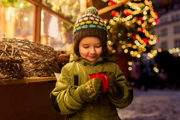 Boldog fiú csésze teát a karácsonyi piacon Stock Kép