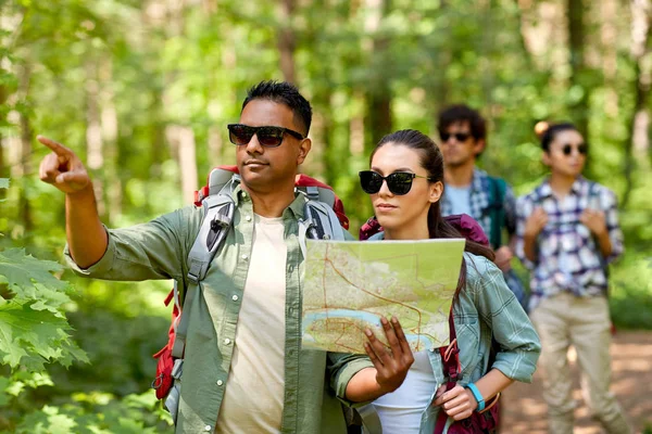 Amis avec carte et sacs à dos randonnée en forêt — Photo