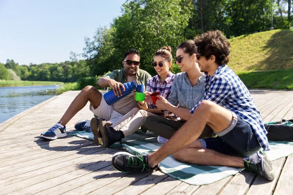 Amigos felices tomando té del termo en verano —  Fotos de Stock