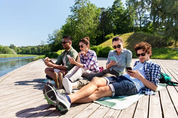 朋友与智能手机在湖码头在夏季 — 图库照片