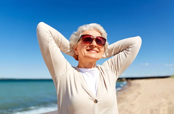 Porträtt av Senior Kvinna i solglasögon på stranden — Stockfoto