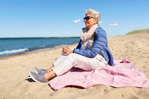 Heureuse femme âgée en veste sur la plage — Photo