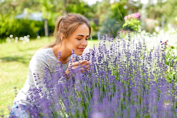 Młoda kobieta pachnąca kwiatami lawendy w ogrodzie — Zdjęcie stockowe
