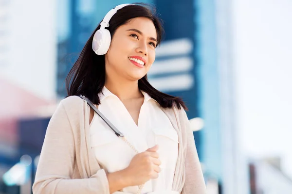 Feliz sorrindo asiático mulher com fones de ouvido na cidade — Fotografia de Stock