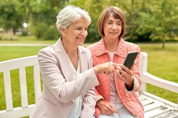 Glada äldre kvinnor med smartphone i sommarparken — Stockfoto