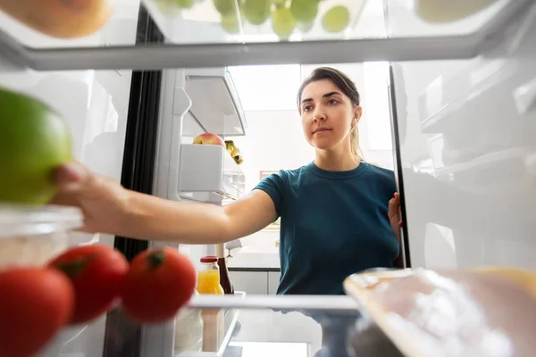 Женщина забирает еду из холодильника дома — стоковое фото