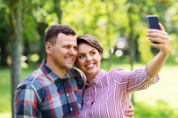 Happy couple in park taking selfie by smartphone — Stock Photo, Image