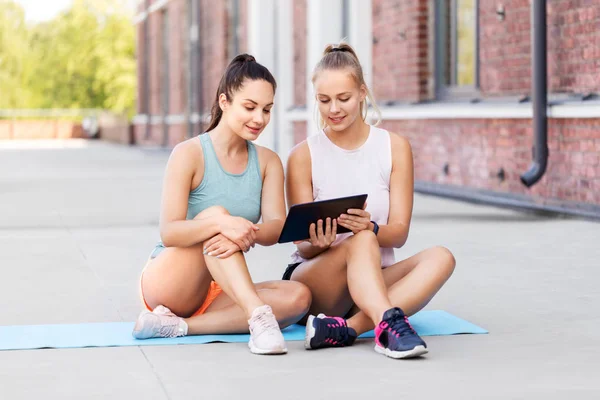 Sportieve vrouwen of vrienden met Tablet PC op het dak — Stockfoto