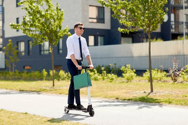 Hombre de negocios con bolsa de compras a caballo scooter —  Fotos de Stock