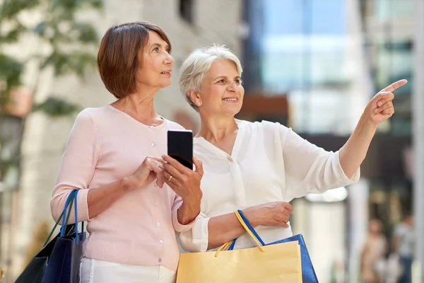 Régi nők bevásárlótáskákat és mobilját a városban — Stock Fotó