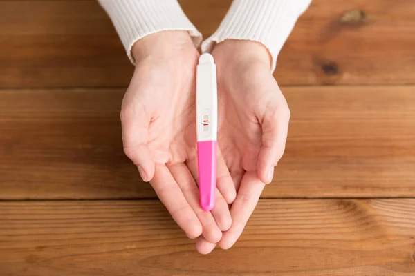 Kobieta ręce trzymając pozytywny test ciążowy — Zdjęcie stockowe