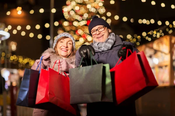 Vecchia coppia al mercatino di Natale con shopping bags — Foto Stock