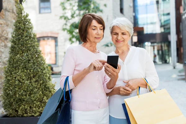 Gamla kvinnor med shoppingväskor och mobiltelefon i City — Stockfoto