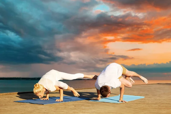 Pareja haciendo yoga lado grúa pose al aire libre —  Fotos de Stock