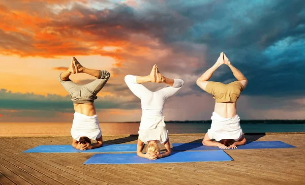 Pessoas fazendo ioga headstand no tapete ao ar livre — Fotografia de Stock