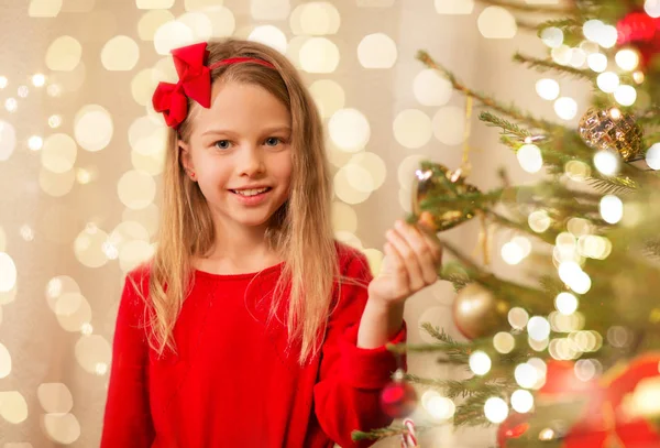 Happy girl in red decorating christmas tree — Stock Photo, Image