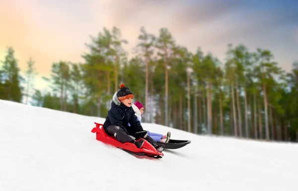 Happy kids sliding on sleds down hill in winter — Stock Photo, Image