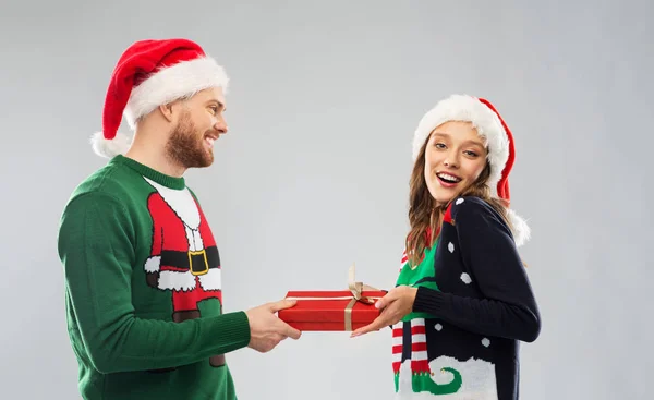 Feliz pareja en suéteres de Navidad con caja de regalo Imagen de archivo