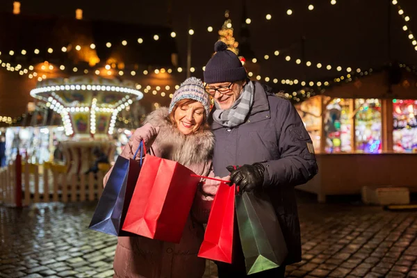一对老夫妇带着购物袋在圣诞市场上 — 图库照片