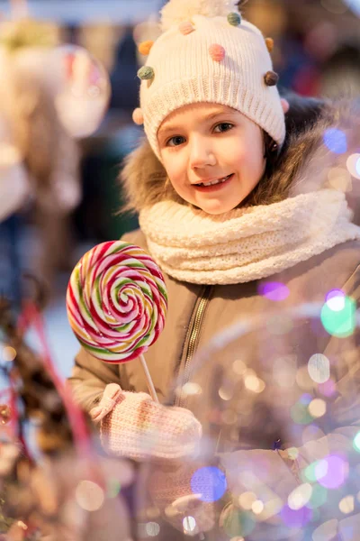 Litle dziewczyna z wielkim lizak na Boże Narodzenie rynku — Zdjęcie stockowe