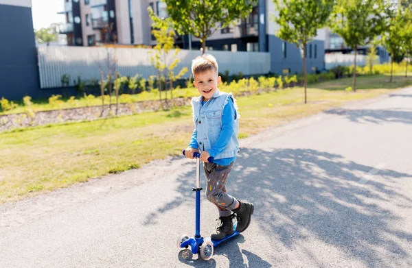 Счастливый мальчик катается на скутере по городу — стоковое фото