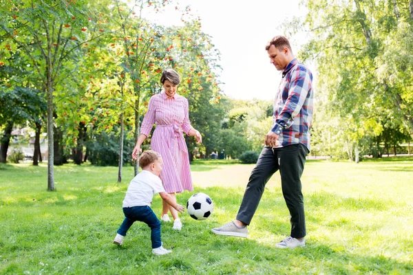 Šťastná rodina hraje fotbal v letním parku — Stock fotografie