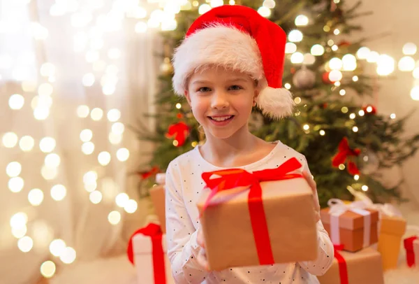 Smiling girl in santa hat with christmas gift — Stock Photo, Image