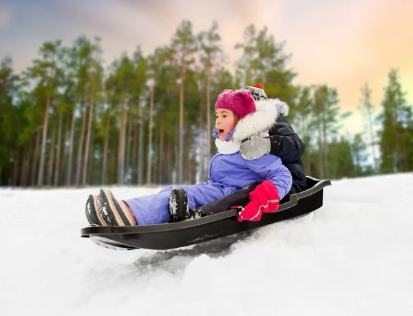 Маленькі діти ковзають на санчатах на пагорбі взимку — стокове фото