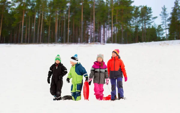 Счастливые маленькие дети с санками зимой — стоковое фото