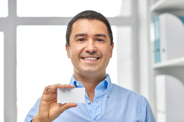 Улыбающийся бизнесмен с визиткой в офисе — стоковое фото
