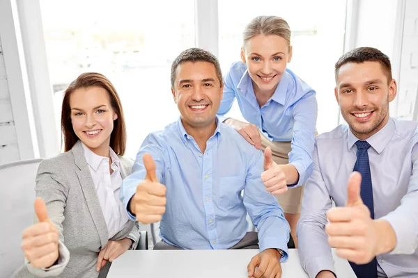 Happy business team showing thumbs up at office — Stock Photo, Image