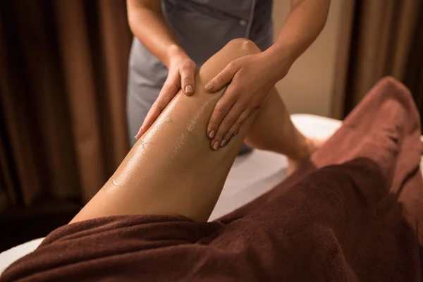 Woman lying and having leg massage with gel at spa — Stock Photo, Image