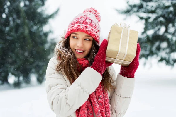 Щаслива молода жінка з різдвяним подарунком взимку — стокове фото