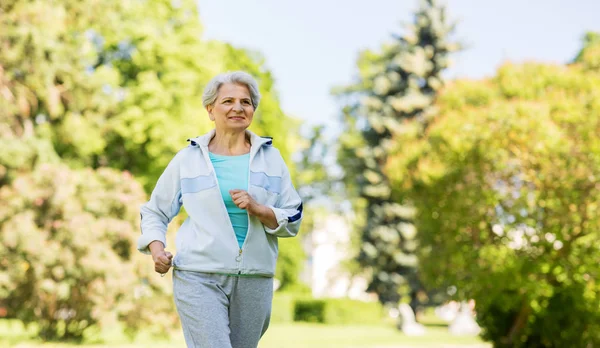 Старшая женщина бегает по летнему парку — стоковое фото