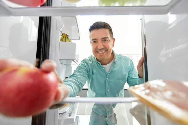 Homme prenant pomme du réfrigérateur à la maison cuisine — Photo