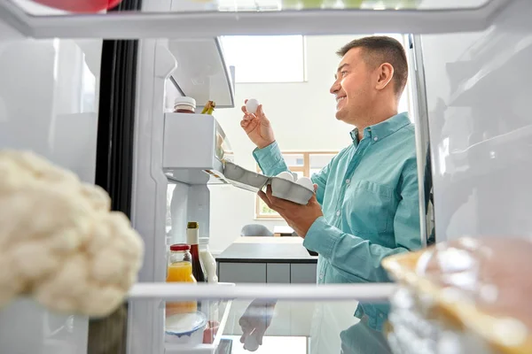 Homme prenant des œufs du réfrigérateur à la cuisine — Photo