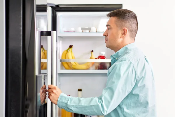 Ember keresi az élelmiszer-hűtőszekrény a konyhában — Stock Fotó