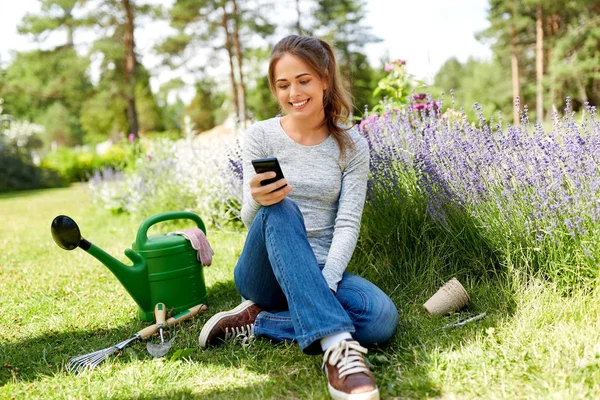 Donna con smartphone e attrezzi da giardino in estate — Foto Stock