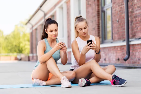 Sportiga kvinnor eller vänner med smartphone på taket — Stockfoto