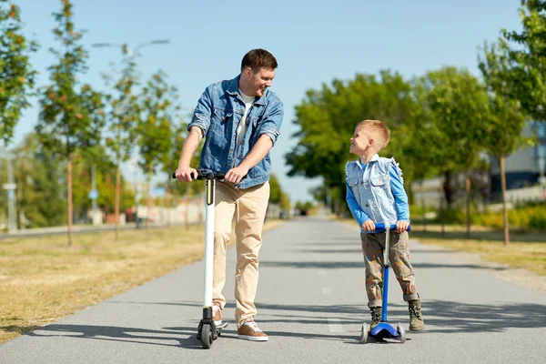 Ojciec i mały syn jazda skutery w miasto — Zdjęcie stockowe