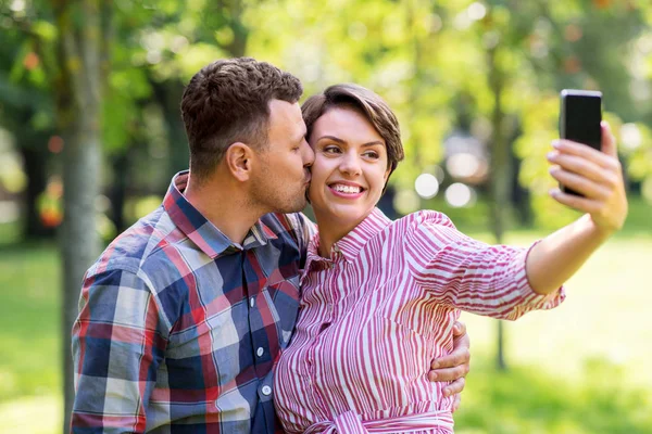 在公园里的一对快乐的夫妇用智能手机自拍 — 图库照片