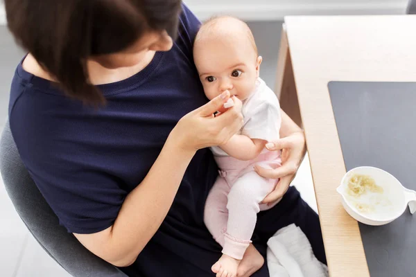 Mutter mittleren Alters füttert kleine Tochter zu Hause — Stockfoto