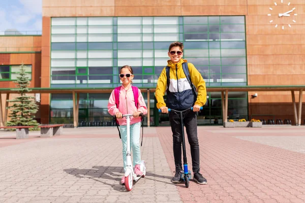 Scooter sürme sırt çantaları ile okul çocukları — Stok fotoğraf
