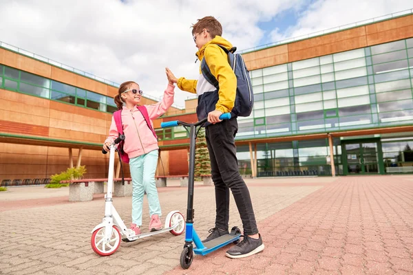 Sırt çantaları ve scooter ile mutlu okul çocukları — Stok fotoğraf