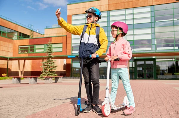 Gelukkige schoolkinderen met scooters die selfie maken — Stockfoto