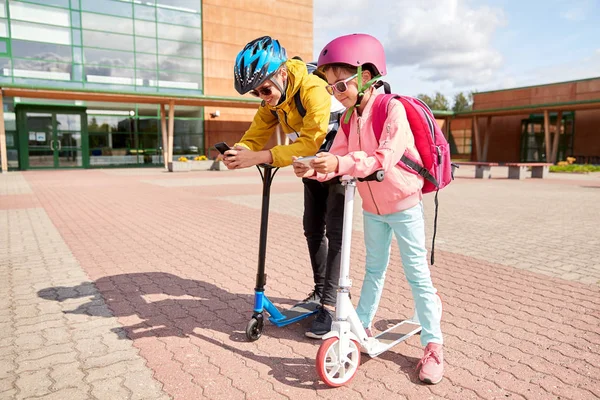 Schoolkinderen met smartphones en scooters — Stockfoto